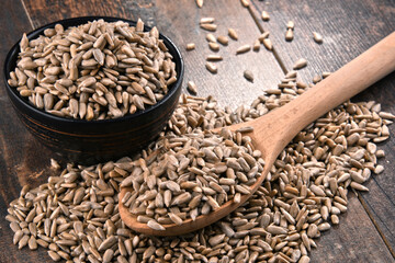 Composition with bowl of shelled sunflower seeds on wooden table