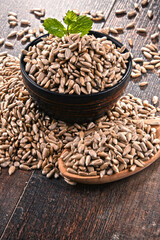 Composition with bowl of shelled sunflower seeds on wooden table