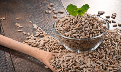 Composition with bowl of shelled sunflower seeds on wooden table