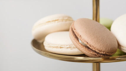 Macaroon cakes in white, brown and green on a golden cake stand. Festive table setting for birthday. Pastry and bakery concept. sweet bar with muffins cakes and sweets in area of wedding party