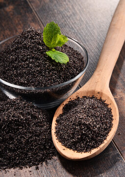 Composition with bowl of poppy seeds on wooden table