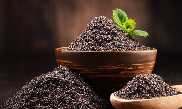 Composition with bowl of poppy seeds on wooden table
