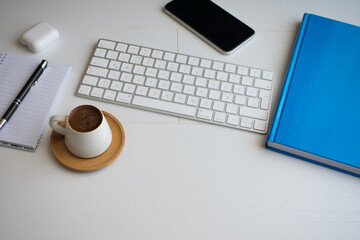 a cup of coffee, notepad, smartphone and keyboard on the office desk