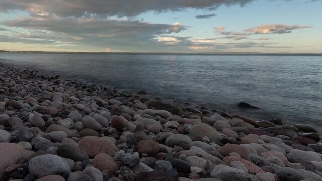 Time lapse footage of rocky beach at sunset and rainbow in a far