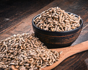 Composition with bowl of shelled sunflower seeds on wooden table