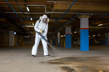 worker in hazmat suit is making disinfection outdoors, coronavirus decontamination for people...