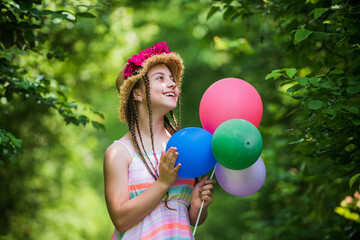 little girl has fresh blossoming flower of roses in hat. flower composition. Beautiful girl in straw hat hold balloons. happy childhood. beautiful girl with party balloons. Think green