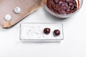 Forming chocolate crinkle cookies. Rolling balls of dough in the sugar powder. Step 8