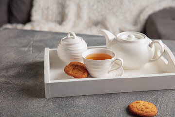 Close-up delicious tea and cakes on wooden grey table. White wooden tray with tea set. The concept of home atmosphere and comfort, romantic date, winter, home comfort, indoors, Christmas or New Year.
