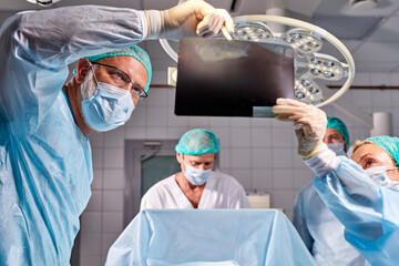 caucasian surgical team talking about X-ray in an operating theater, discuss x-ray before interfere...