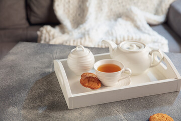 Delicious tea and cakes on wooden grey table, closeup. White wooden tray with tea set. The concept of home atmosphere and comfort, romantic date, winter, home comfort, indoors, Christmas or New Year.