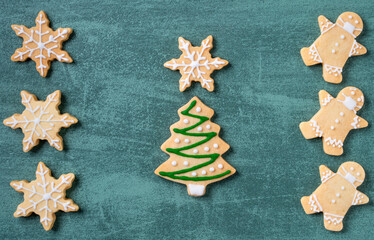 Top view of Christmas tree and snowflake cooikes with gingerbread man wearing mask.