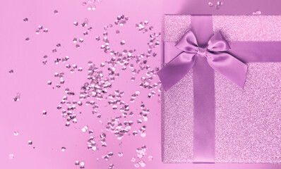Big present box with  bow on a colorful background with sequins. Christmas or birthday gift.
