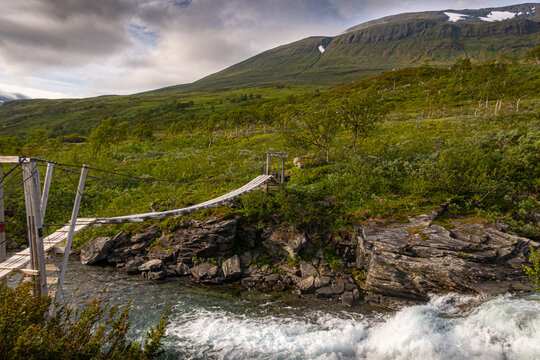 Hiking bridge over a wild river thru the mountains of lappland