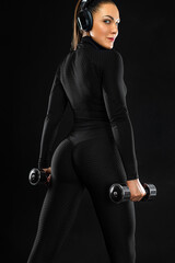 Athlete with dumbbells make fitness exercises on black background. Sporty fit woman in sport concept.