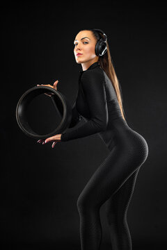 Woman athlete in black sportswear. Young gymnastics girl with pilates fitness ring wheel on black background in yoga studio classroom.