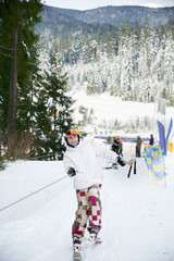 Tourist at ski resort lifting on the ski drag lift rope, trying to keep balance. Amazing landscape...