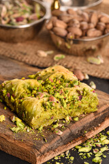 Turkish ramadan dessert Baklava with pistachio. Pistachio turkish style Gaziantep baklava presentation and service. World famous baklava making in Gaziantep. Baklava presentation on wooden board. 