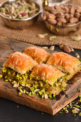 Turkish ramadan dessert Baklava with pistachio. Pistachio turkish style Gaziantep baklava presentation and service. World famous baklava making in Gaziantep. Baklava presentation on wooden board. 
