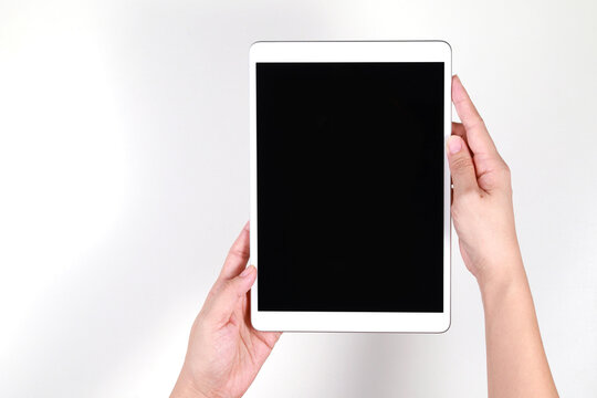 Top view image of woman hands holding a blank screen tablet computer against a white background.