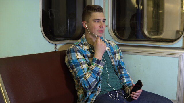 A Young Man Speaks On The Phone Through Headphones In A Subway Train. Old Subway Car