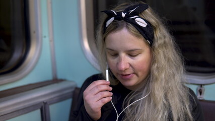 A pregnant woman is talking on the phone through headphones to a subway train. Old subway train car