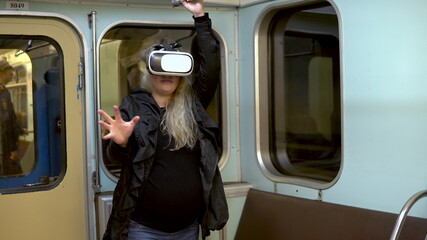 Pregnant woman in virtual reality helmet in subway train. Old subway train car