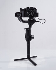 Mirrorles professional cameras with a gimbal camera stabilizer. Video Camera Gimbal Stabilization Tripod System on a white background. Gimbals Stabilization System with Mirrorless Camera.