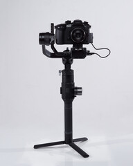 Mirrorles professional cameras with a gimbal camera stabilizer. Video Camera Gimbal Stabilization Tripod System on a white background. Gimbals Stabilization System with Mirrorless Camera.