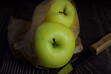 Close up, apple on rustic table partially covered by a kraft paper bag.