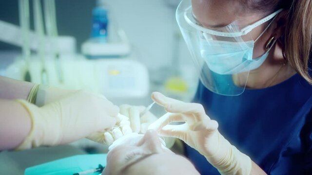 Unknown orthodontist and assistant at work with a female patient