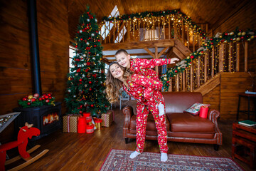 A young mother and son playing near the Christmas tree. Family in red Christmas pajamas. Christmas homeliness. Holidays and New Year's gifts