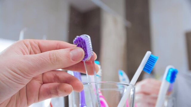 Changing toothbrush. Female hand replacing old dirty worn out tooth brush with a new one. Closeup, slow motion. Shot in 60 fps, slowed down to 24 fps.