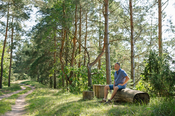 Portrait of a man in the forest. The traveler stopped to rest and sat down by the road