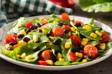 Mexican salad with black beans, corn,tomatoes,lettuce and pepper on wooden table