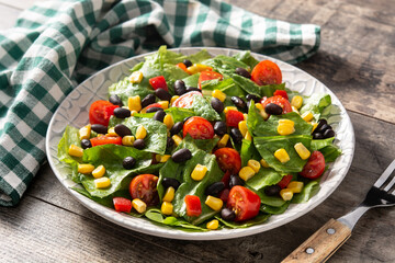 Mexican salad with black beans, corn,tomatoes,lettuce and pepper on wooden table