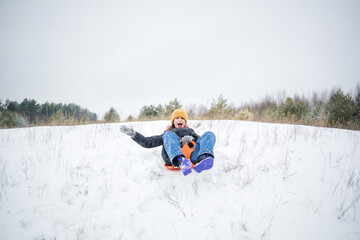 winter kids fun. child is rolling down mountain on tray. first snow in coniferous forest