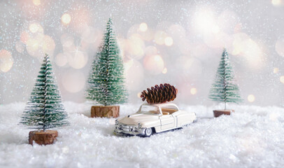 Cone on the toy car with blurred background and snow. Magic atmosphere, concept of Christmas holidays. Greeting card.