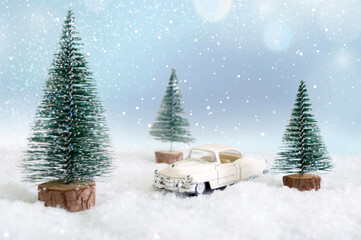 Toy car in the forest among the snowdrifts with blurred background. Magic atmosphere, concept of Christmas holidays. Greeting card.
