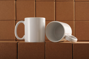 two white mugs for sublimation on the background of cardboard craft boxes