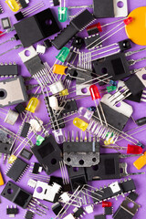 Radio components on a purple background. There are microcontrollers, transistors, green, red, blue...