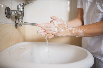 Hands washing. Person washing their hands with soap. Doctor washing hands after the surgery wearing...
