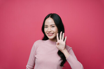 Portrait of asian woman showing four fingers gesture pose isolate on pink background.