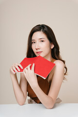 Portrait of beautiful asian woman with a red book at office desk.