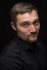 Obraz premium Closeup portrait of handsome man with a beard in black shirt. Isolated on black background
