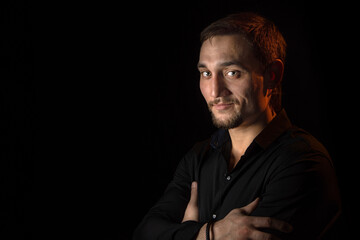 Closeup portrait of handsome man with a beard in black shirt. Isolated on black background
