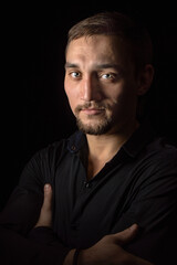 Fototapeta premium Closeup portrait of handsome man with a beard in black shirt. Isolated on black background