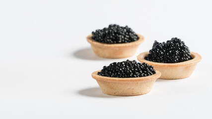 
black caviar on a white plate. tartlet with black caviar. snack.