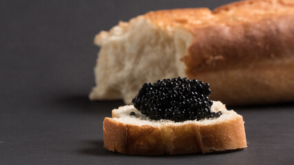 
black caviar with bread on black background