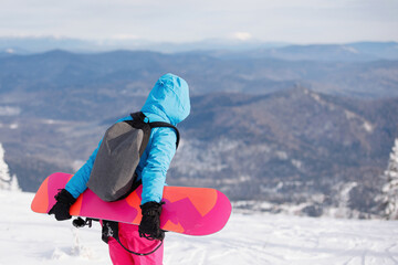 Woman snowboarder walks on the snowy mountain